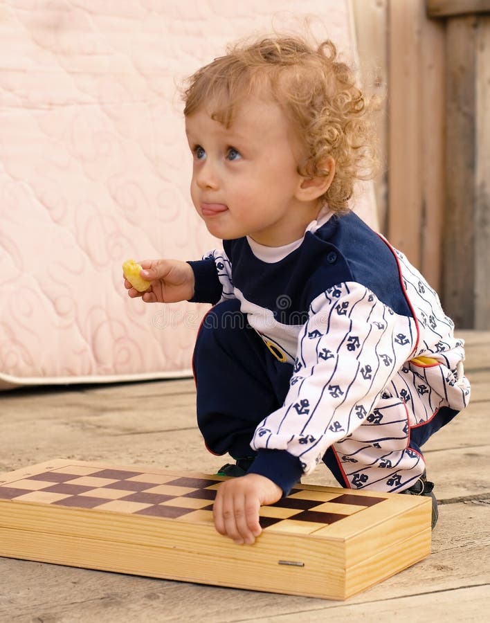 Weinig krullende jongen houdt een schaakbord