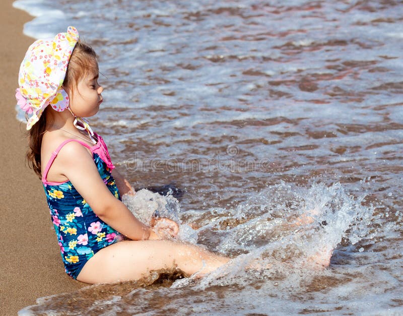 Weinig leuke zitting van het kindmeisje op overzees strand stock afbeelding Weinig leuke zitting van het kindmeisje op overzees strand stock afbeelding