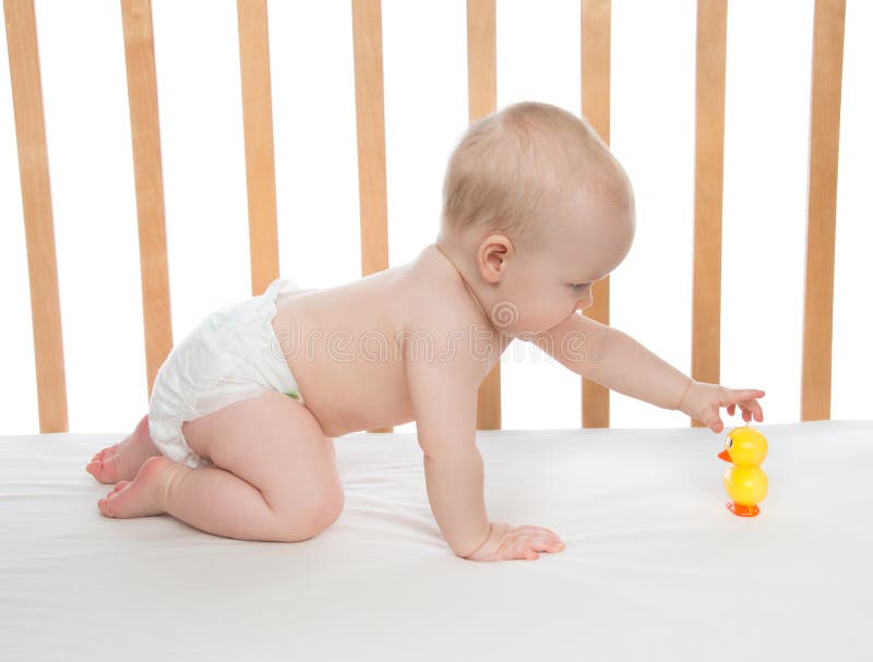 Weinig meisje die van de kindbaby in bed met stuk speelgoed eend kruipen royalty-vrije stock fotografie Weinig meisje die van de kindbaby in bed met stuk speelgoed eend kruipen royalty-vrije stock fotografie