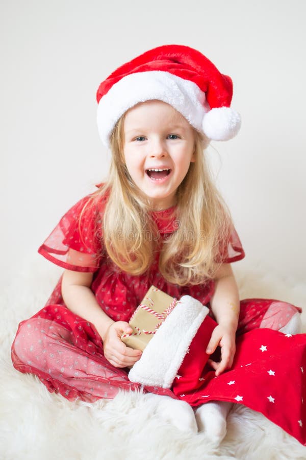 Weinig Mooi Meisje in Santa Hat Red Party Dress die op Kerstmis en Nieuwjaar wachten stock afbeelding Weinig Mooi Meisje in Santa Hat Red Party Dress die op Kerstmis en Nieuwjaar wachten stock afbeelding