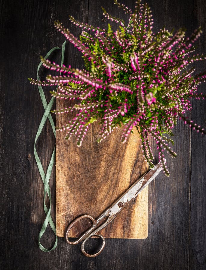 Weinlese scissors mit Band- und Herbstblumen auf rustikalem hölzernem Hintergrund
