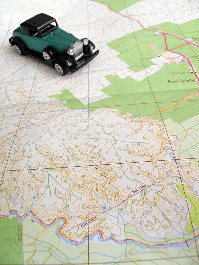 A travel concept photograph of a quaint old fashioned car model on an open map. Selective focus is on details of map. Car is slightly out of focus. Concept image for self drive road trip, free and easy traveling theme. A travel concept photograph of a quaint old fashioned car model on an open map. Selective focus is on details of map. Car is slightly out of focus. Concept image for self drive road trip, free and easy traveling theme.