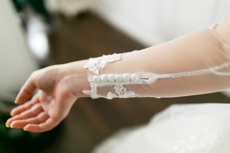 Weiße Knöpfe auf dem Spitzen- Ärmel eines Hochzeitskleides Nahaufnahme von Braut ` s Hand lizenzfreies stockbild Weiße Knöpfe auf dem Spitzen- Ärmel eines Hochzeitskleides Nahaufnahme von Braut ` s Hand lizenzfreies stockbild