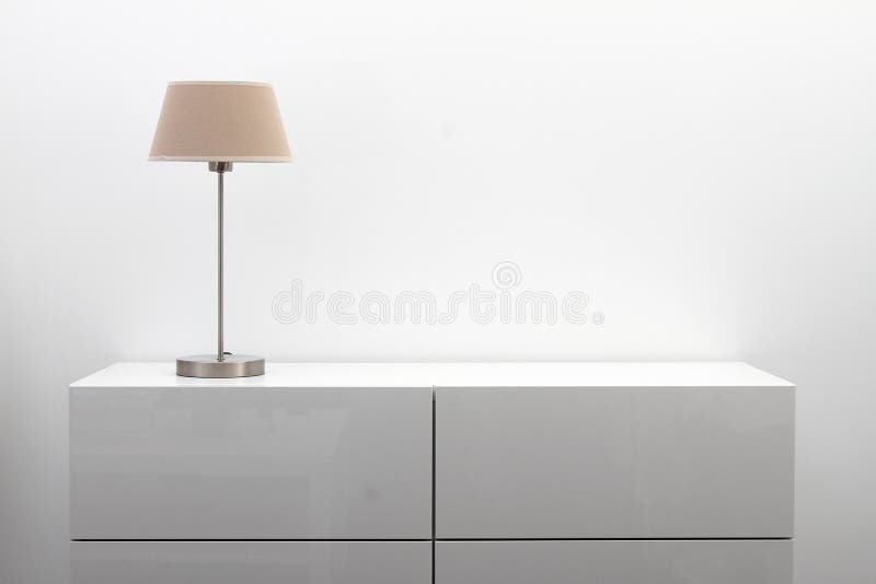 Weiße Kommode mit Tischlampe im hellen Minimalismusinnenraum
