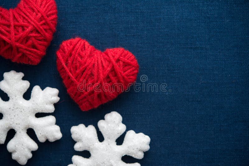 White snowflakes and red wool hearts on blue canvas background. Merry christmas card. Winter holidays. Xmas theme. Happy New Year. White snowflakes and red wool hearts on blue canvas background. Merry christmas card. Winter holidays. Xmas theme. Happy New Year.