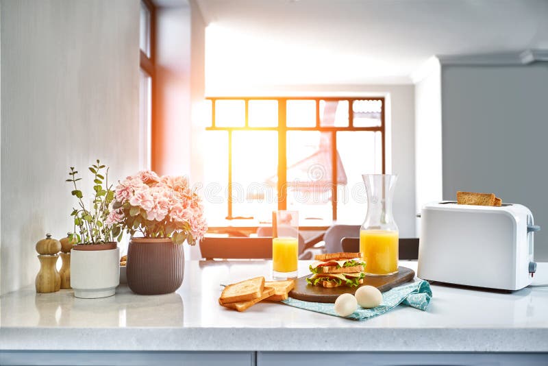 Weißer elektrischer Brottoaster mit Orangensaft mit Sandwich auf Küchentisch Frühstück in der gemütlichen Küche Sun-Aufflackern lizenzfreie stockfotos Weißer elektrischer Brottoaster mit Orangensaft mit Sandwich auf Küchentisch Frühstück in der gemütlichen Küche Sun-Aufflackern lizenzfreie stockfotos