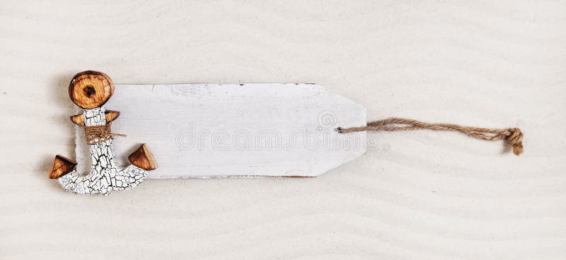 Weißer hölzerner Aufkleber mit einem Anker im Sand Bekanntmachen des Vorstands stockbild Weißer hölzerner Aufkleber mit einem Anker im Sand Bekanntmachen des Vorstands stockbild