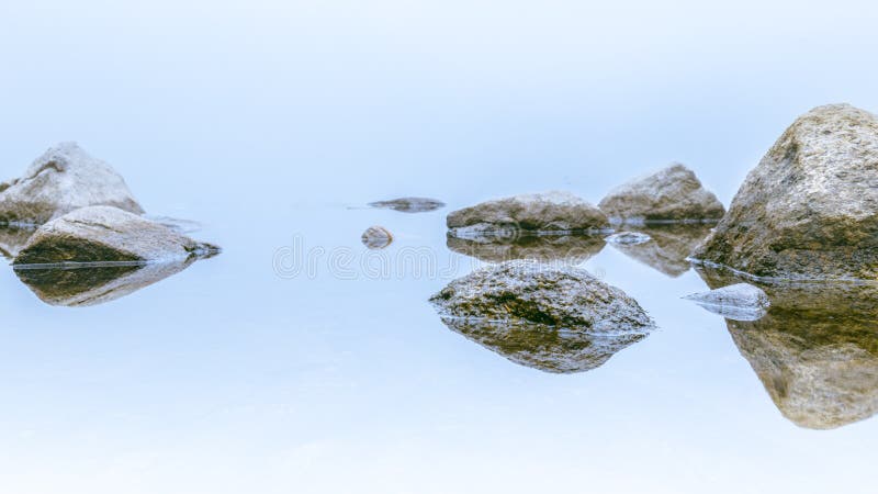 After rainy night, the fog is so thick that the lake cannot be seen. Reflection of the rocks on the water. Lac Georges, Grands-Jardins National Park, Canada. Le Pioui Trail. After rainy night, the fog is so thick that the lake cannot be seen. Reflection of the rocks on the water. Lac Georges, Grands-Jardins National Park, Canada. Le Pioui Trail.