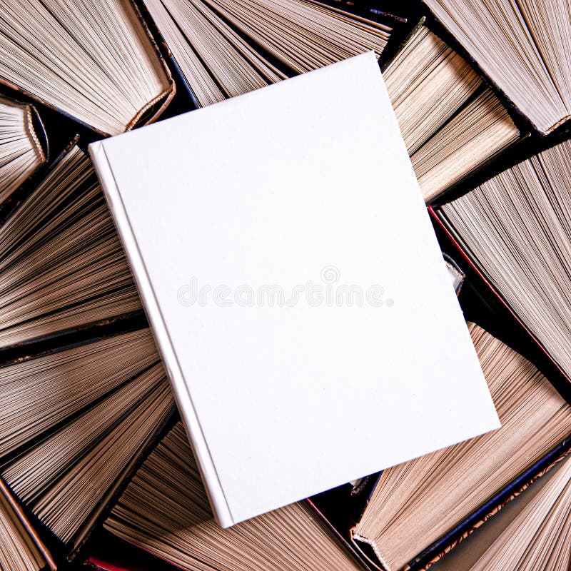 White book in white cover with a place for text lies on multicolored old open books. Top view. White book in white cover with a place for text lies on multicolored old open books. Top view