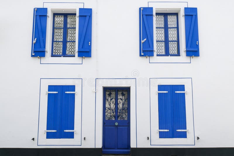 Weißes Fassadenhaus mit blauen Fenstern und den Fensterladen-, offenen und geschlossenenfensterläden stockfoto Weißes Fassadenhaus mit blauen Fenstern und den Fensterladen-, offenen und geschlossenenfensterläden stockfoto