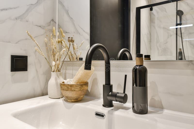 a bathroom sink with some flowers in the bowl and a mirror on the wall behind it is a black fae. a bathroom sink with some flowers in the bowl and a mirror on the wall behind it is a black fae