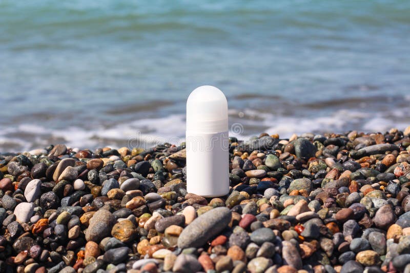 Weißflasche mit Deo. Deodorierende weiße Flasche, die an der Meeresküste am sonnigen Tag steht. Produkt-Mock-up-Idee für Deo-Werbung mit frischem Meeresbrise Duft