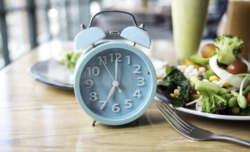 Alarm clock of blue  which schedule of meal for weight loss and Intermittent fasting concept. Alarm clock of blue  which schedule of meal for weight loss and Intermittent fasting concept