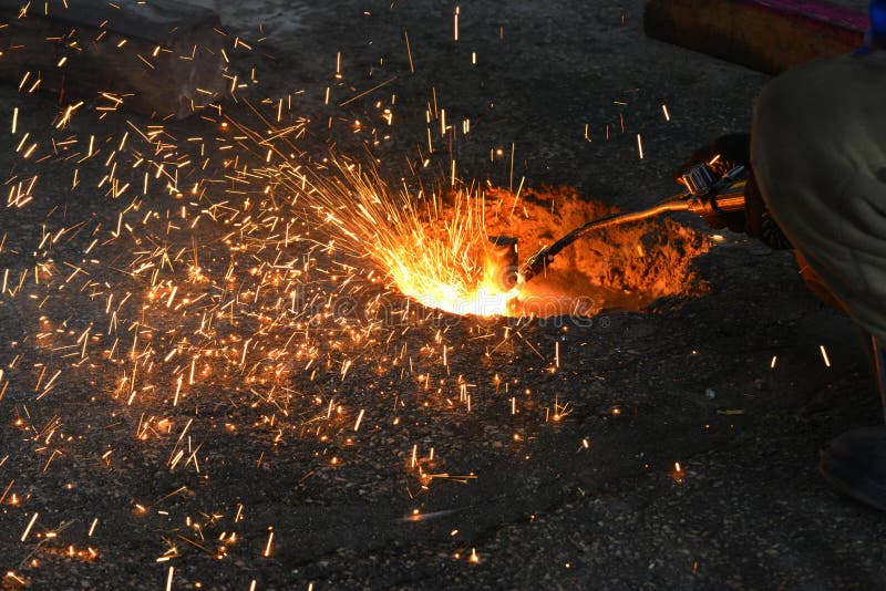 The welder cuts the metal with gas welding and the sparks fly close-up.