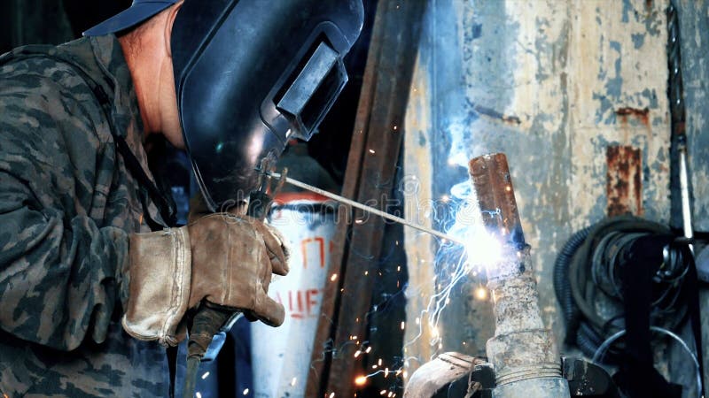 Welder at the factory in welding mask welds metal parts. Frame. Masked welder welding parts. Welding with blue and royalty free stock images Welder at the factory in welding mask welds metal parts. Frame. Masked welder welding parts. Welding with blue and royalty free stock images
