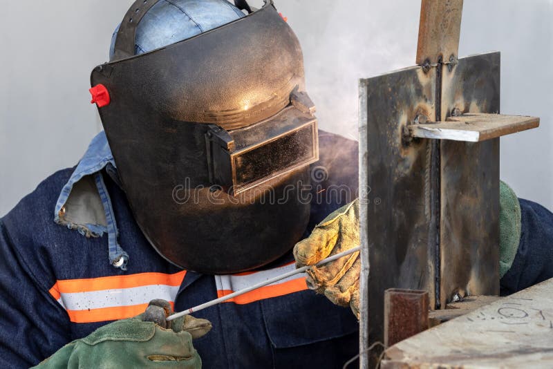Welder qualification. The welder is welding with shielded metal arc welding process to steel plate in vertical position for welder