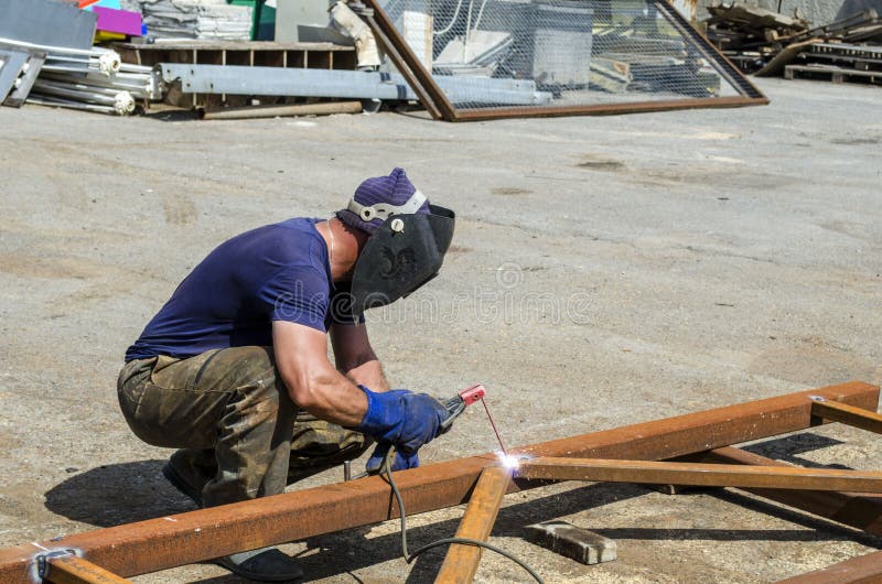 Welder at Work Weld an Iron Construction in a Metal Warehouse