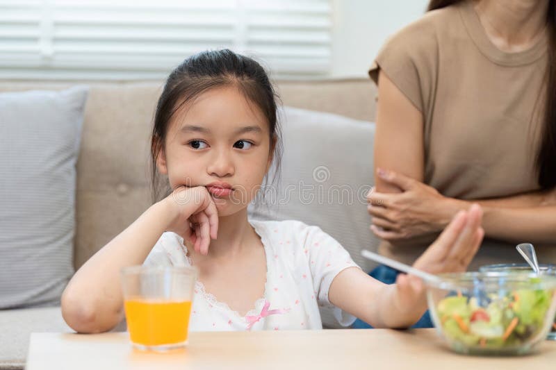 Wellness and healthy choices: Daughter hesitant about eating salad stock photos