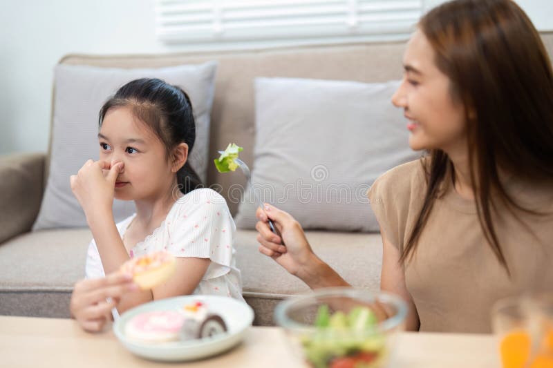 Wellness and healthy eating: Mother encouraging daughter to eat salad stock photography