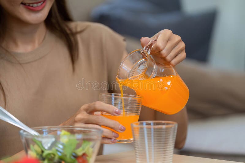 Wellness routine: woman pouring orange juice for a healthy breakfast stock photography
