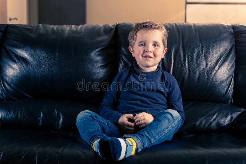 Wenig Junge, der im schwarzen Sofa sitzt lizenzfreie stockfotografie Wenig Junge, der im schwarzen Sofa sitzt lizenzfreie stockfotografie