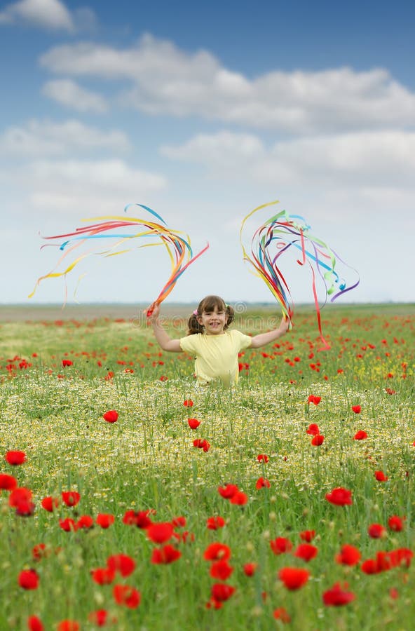 Wenig Mädchen, das mit bunten Bändern auf Wiesenfrühlings-saison wellenartig bewegt lizenzfreies stockbild Wenig Mädchen, das mit bunten Bändern auf Wiesenfrühlings-saison wellenartig bewegt lizenzfreies stockbild