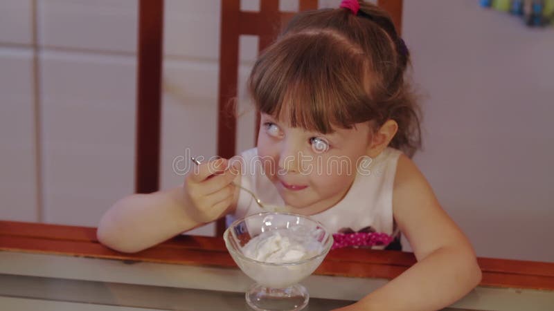 Wenig Mädchen in der Küche zu Hause Eiscreme plaudernd und essen.