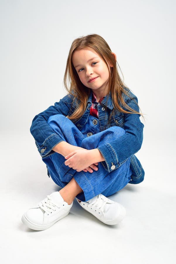 Wenig Mädchen in Jeans sitzt auf dem Boden. Studioschießen lizenzfreie stockfotografie
