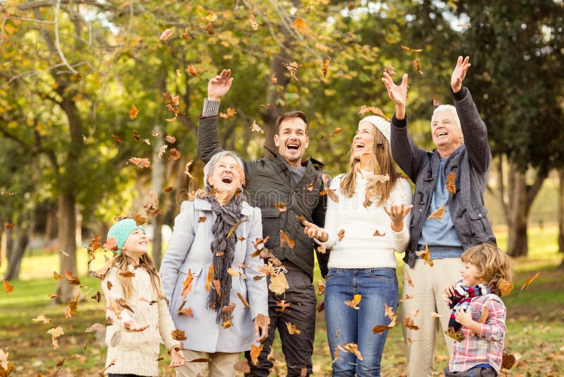 Werfende Blätter der glücklichen Großfamilie herum lizenzfreies stockbild Werfende Blätter der glücklichen Großfamilie herum lizenzfreies stockbild