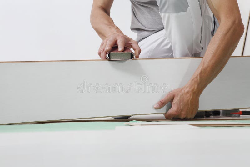 Werkhanden die hout lamineren - witte vloer installeren. nauwkeurige afwerking met zandpapier. renovatie van houten vloeren