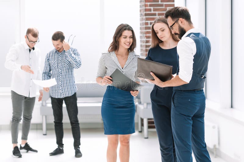 Werknemers die bedrijfsdocumenten in de bureauhal bespreken stock afbeelding Werknemers die bedrijfsdocumenten in de bureauhal bespreken stock afbeelding