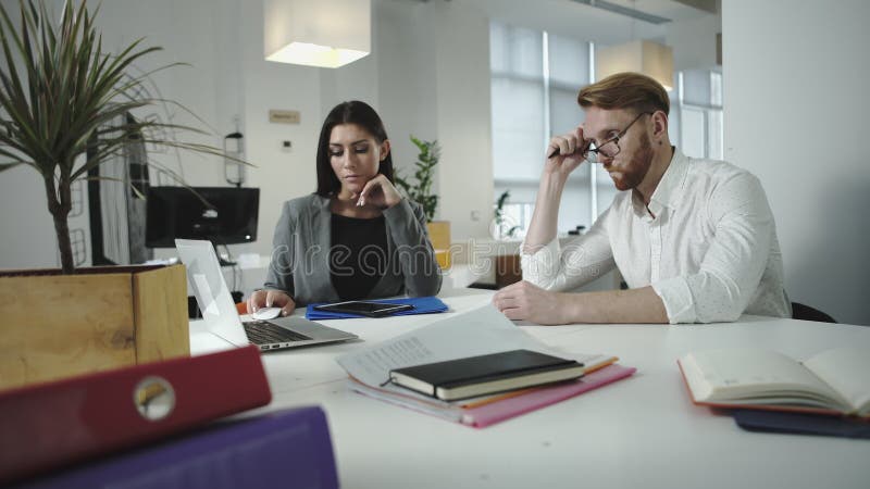 Werknemers die het werk in het bureau bespreken samen het kijken op laptop