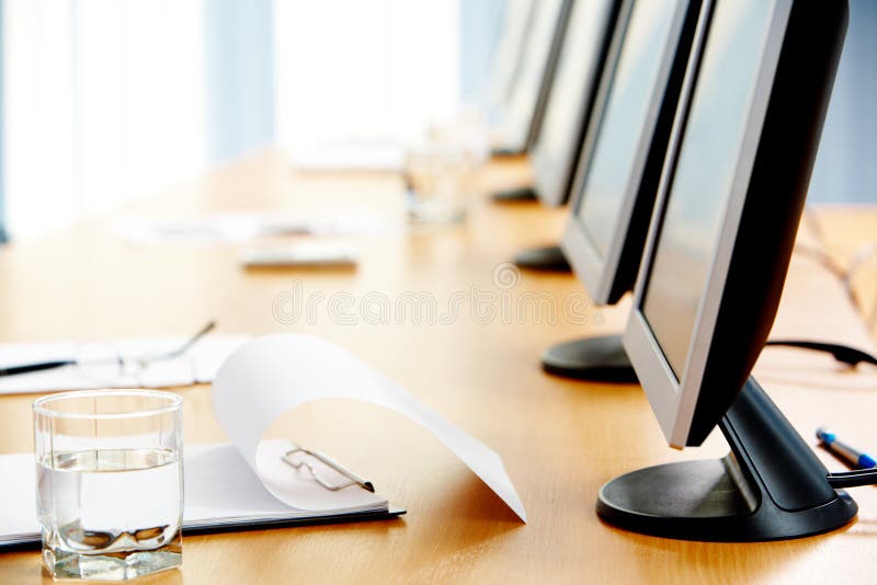 Close-up of workplace with notepad, glass of water and monitors on it. Close-up of workplace with notepad, glass of water and monitors on it