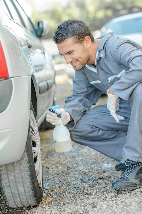 Werktuigkundige die een wieldop schoonmaken stock afbeeldingen Werktuigkundige die een wieldop schoonmaken stock afbeeldingen