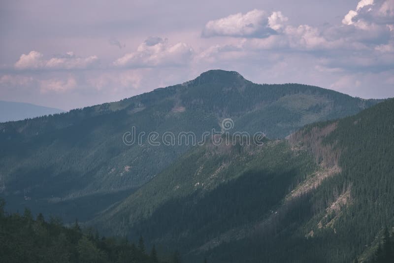 Western carpathian mountain tops in autumn covered in mist or clouds with blue cast and multidimensional lines - vintage old film