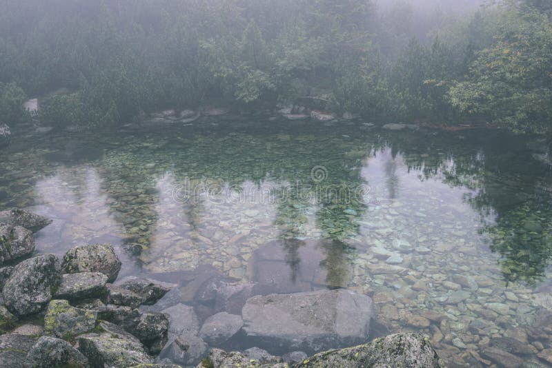 Mlhavé ráno pohled v mokré horské oblasti ve slovenských Tatrách. panorama horského jezera - vzhled vintage filmu