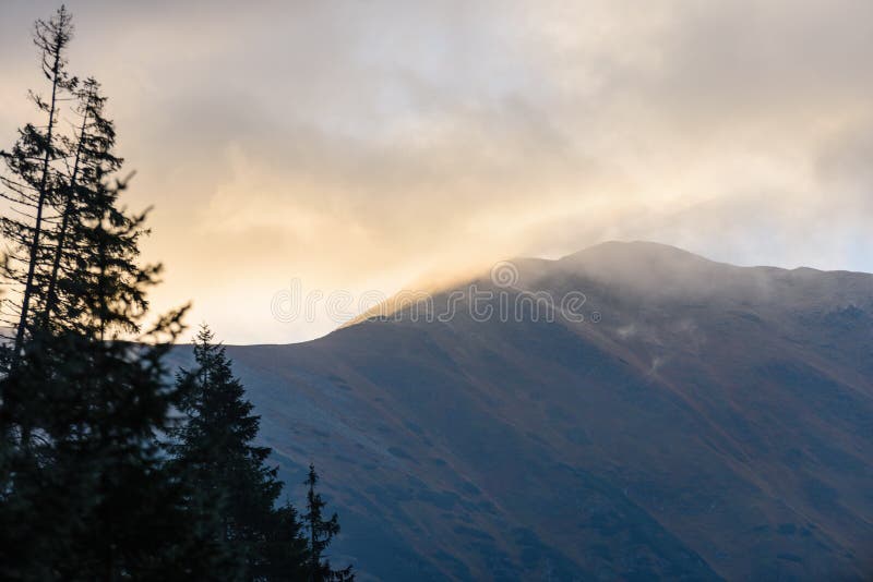 Mountain tops in autumn covered in mist or clouds in sunrise li