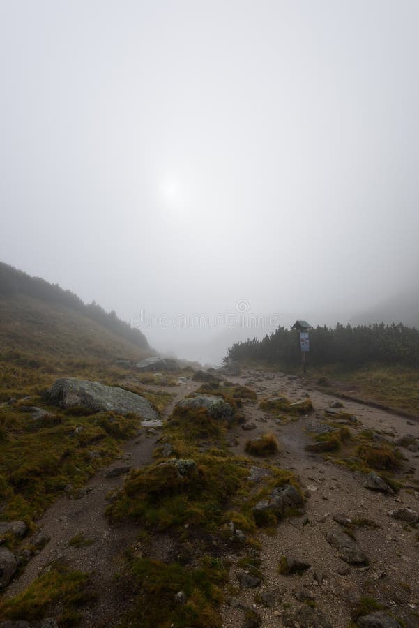 Mountain tourist trail in autumn covered in mist