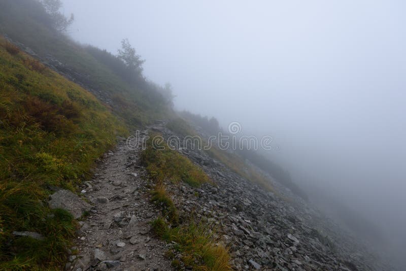 Mountain tourist trail in autumn covered in mist