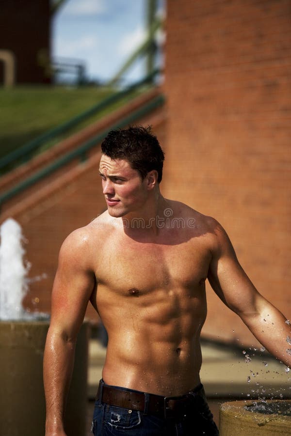 A young bodybuilder cooling off in a fountain on a hot summer day. A young bodybuilder cooling off in a fountain on a hot summer day.