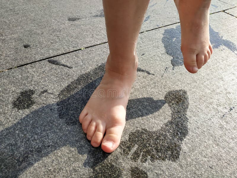 Wet footprints on the road, baby`s bare feet.close-up. Summer heat.