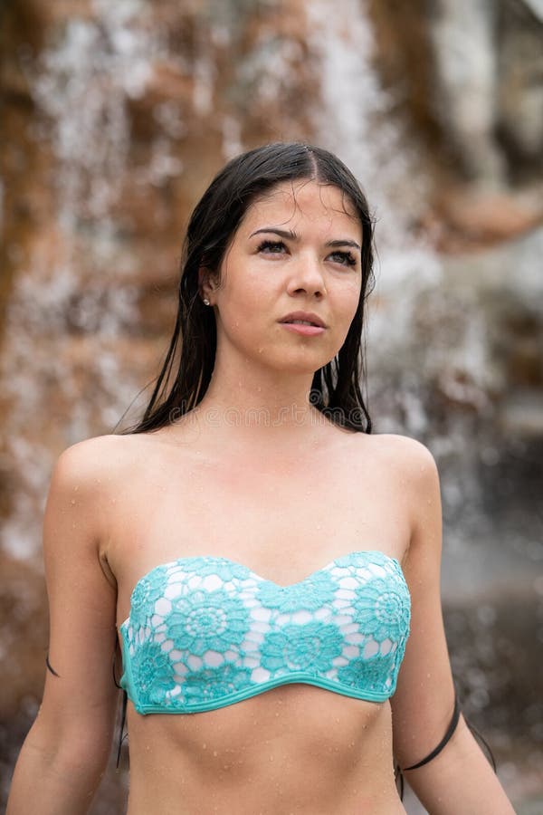 Wet girl in a bathing suit looks into the distance. In the background is a rock and a waterfall stock image Wet girl in a bathing suit looks into the distance. In the background is a rock and a waterfall stock image