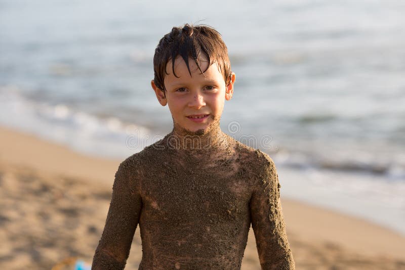 Wet sand dirty boy kid smiling while playing at beach.Warm sunset light. Family summer travel vacations at sea or ocean stock photos Wet sand dirty boy kid smiling while playing at beach.Warm sunset light. Family summer travel vacations at sea or ocean stock photos