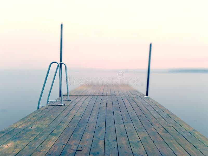 Wet pier in smooth water of sea bay. Mole anchored with steel poles into bottom