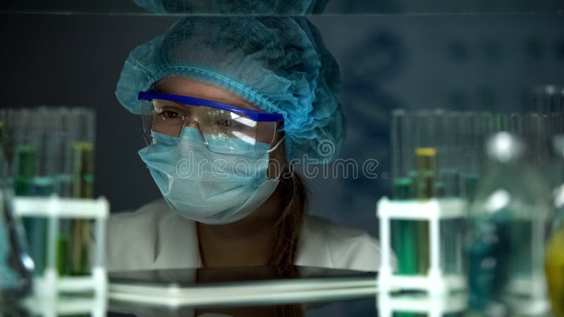 Wetenschapper in het beschermende eenvormige bekijken steekproeven in buizen, de chemische industrie stock fotografie Wetenschapper in het beschermende eenvormige bekijken steekproeven in buizen, de chemische industrie stock fotografie