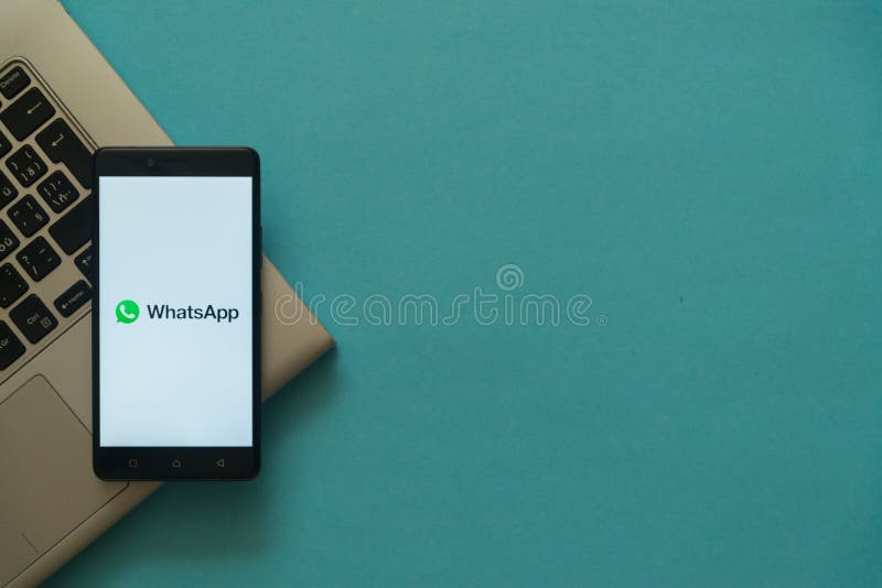 Whatsapp logo on smartphone placed on laptop keyboard.