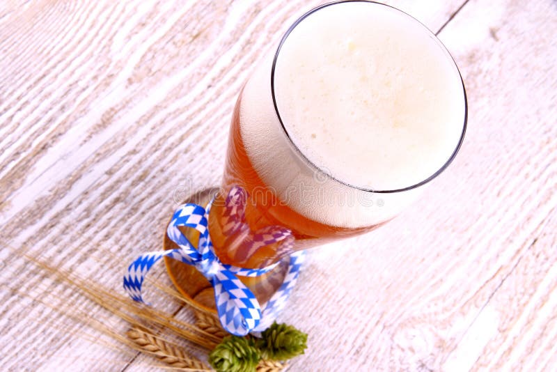 Wheat beer in glass with blue ribbon on white wood background