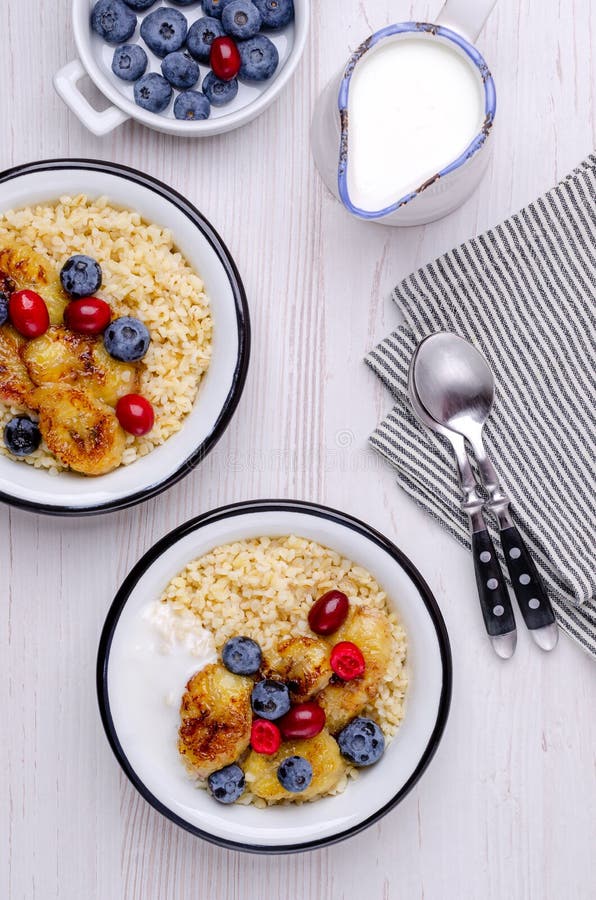 Wheat porridge with fruit and berries in a dish on a wooden background. Selective focus