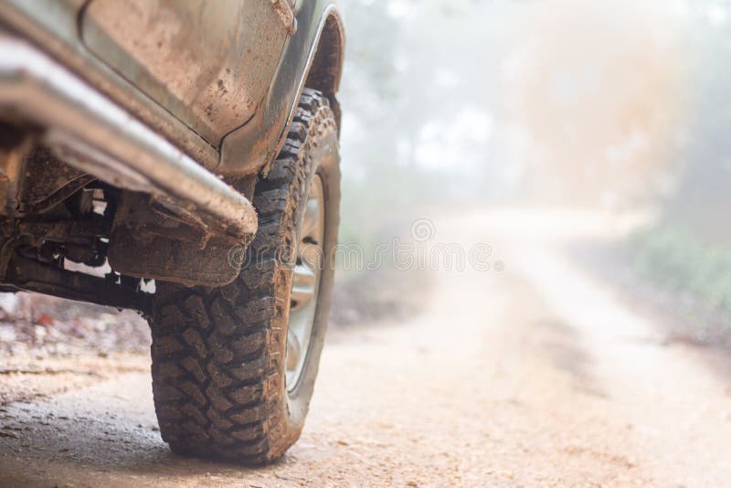 Wheel closeup in a countryside landscape with a muddy road, Off-