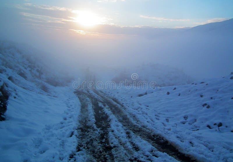 Wheel and human track on snow covered mountain road